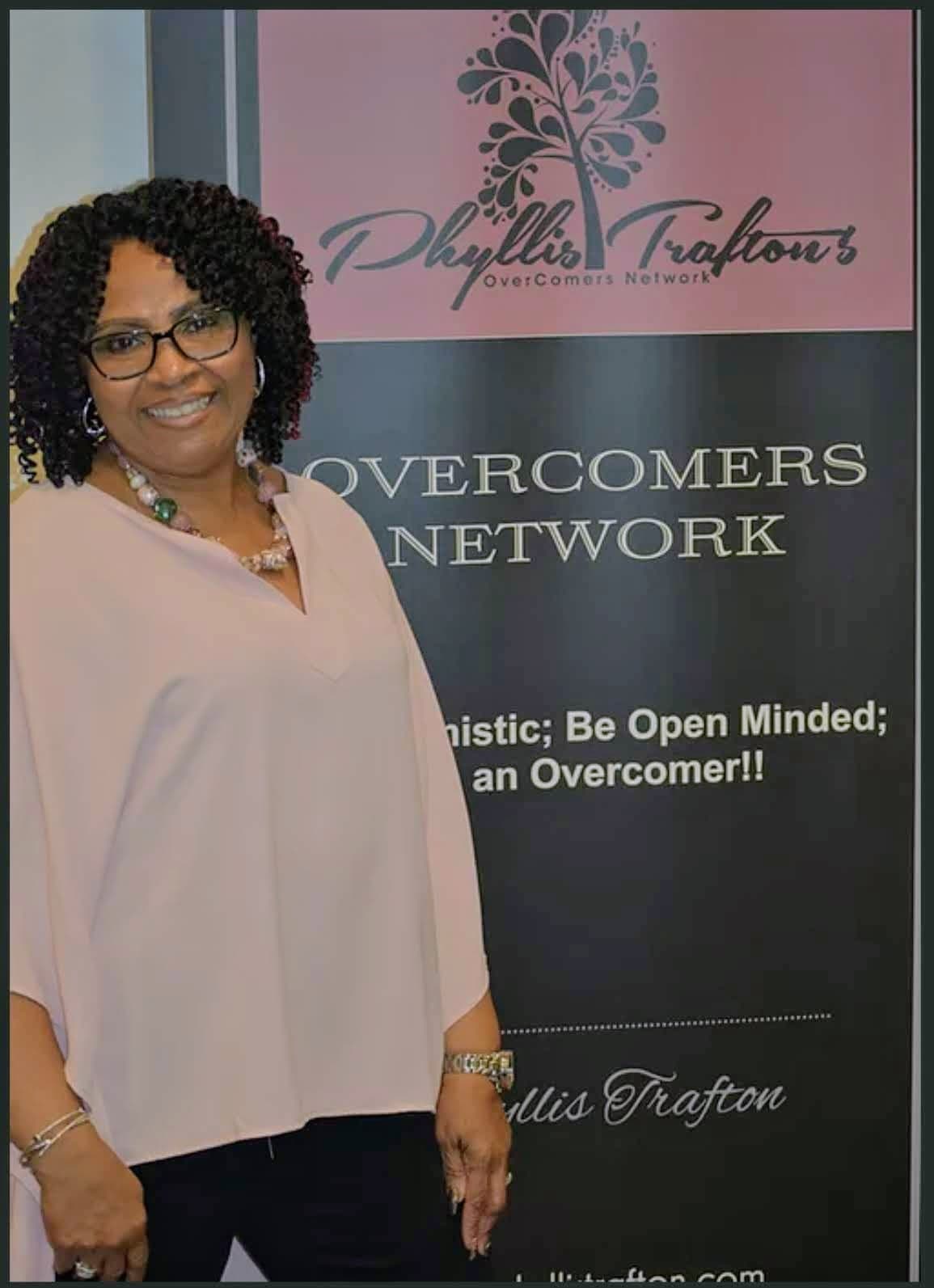 Phyllis Trafton at an event booth with the Overcomers Network pull-up banner